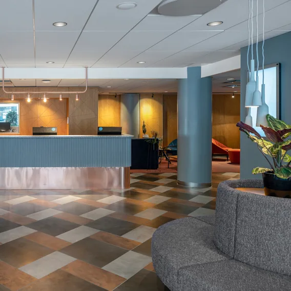 Receptionen på Quality Hotel The Mill i Malmö med blå väggar och brunt grafiskt mönstrat golv. 