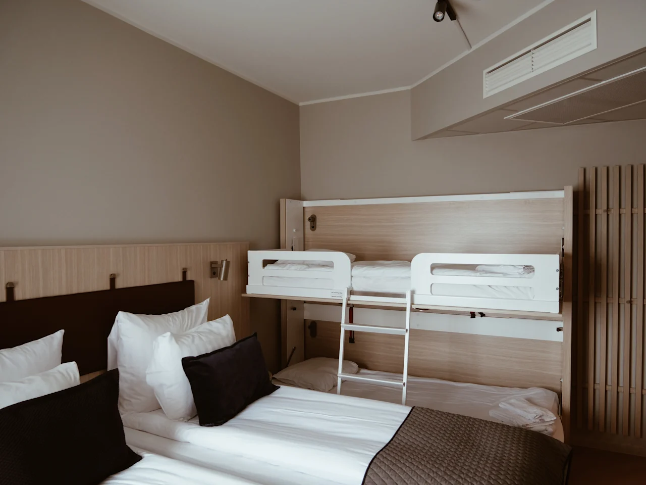 Et moderne og komfortabelt hotellrom med en stor seng og en innebygd køyeseng, designet for flere gjester.