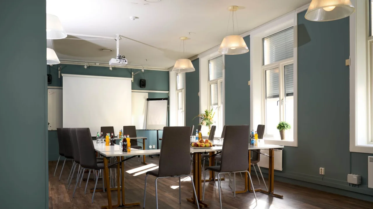 Conference room with tables, chairs, snacks, and a projector, suggesting a meeting or workshop setting.