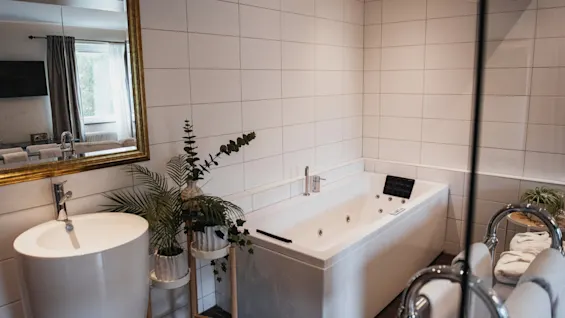 A tranquil and contemporary bathroom designed for relaxation, featuring a large soaking tub, a modern sink, and refreshing greenery.