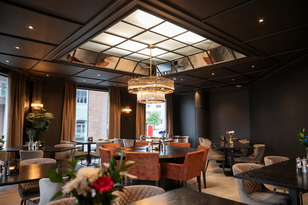 En sofistikeret spisestue med forskellige siddepladser, en fremtrædende lysekrone og en lysende loftfunktion.