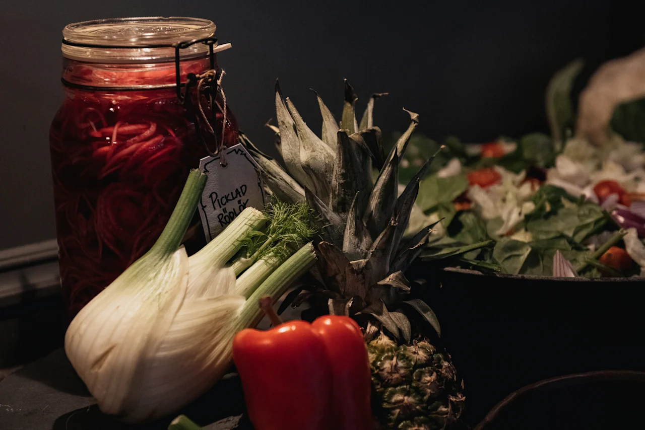 A fresh food display featuring pickled red onions labeled Picklad Rodlok, pineapple, and vegetables at Home Hotel Kung Oscar.