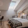 Viihtyisä hotellihuone, jossa kaksi erillistä sänkyä, työpöytä, televisio ja kattoikkuna, luontoaiheisella sängynpäädyllä.