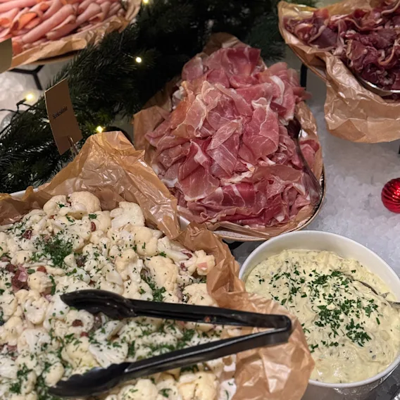 En festlig buffet med ulike kalde retter, inkludert skivet kjøtt og kremete salater, servert med tang.