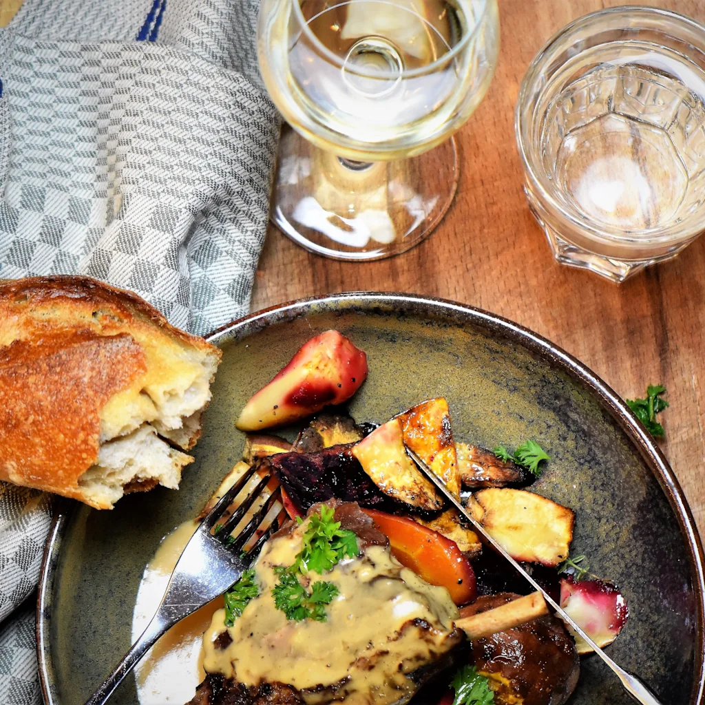 Gourmet-ateria pääruoalla, paahdetuilla kasviksilla, tuoreella leivällä ja juomilla, valmiina nautittavaksi Home Hotelissa.