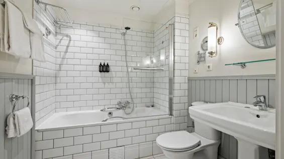 A bright and clean bathroom featuring a bathtub with a shower, a toilet, and a sink, all in a modern design.