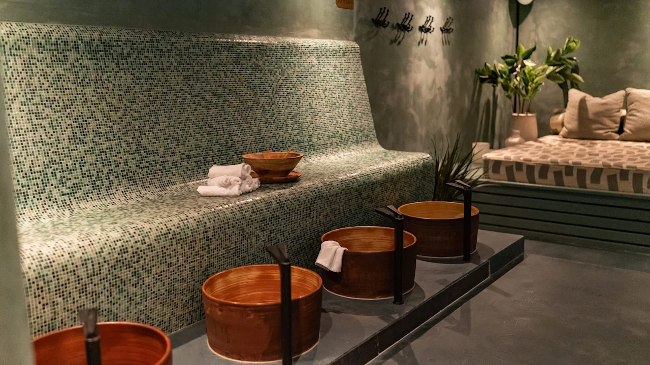 Et rolig spa-rom med en mosaikkflislagt benk, fotbad og et komfortabelt avslapningsområde.