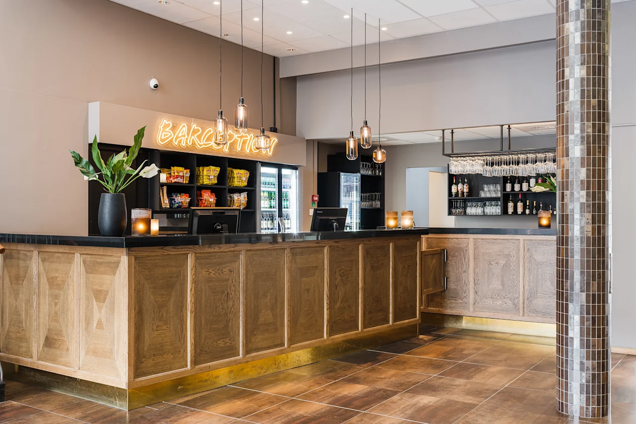 Modern hotel reception and bar in light wood with a glowing Barception sign on the wall.