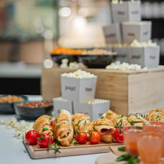 En pausebuffet for konferanser med fylte croissanter, cherrytomater og popkornesker.