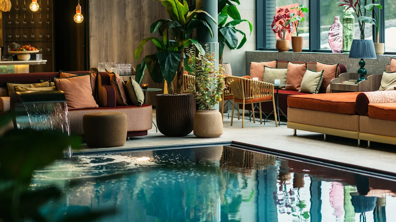 A serene indoor pool area at Lily Country Club with a cozy lounge, lush plants, and large windows overlooking a winter scene.
