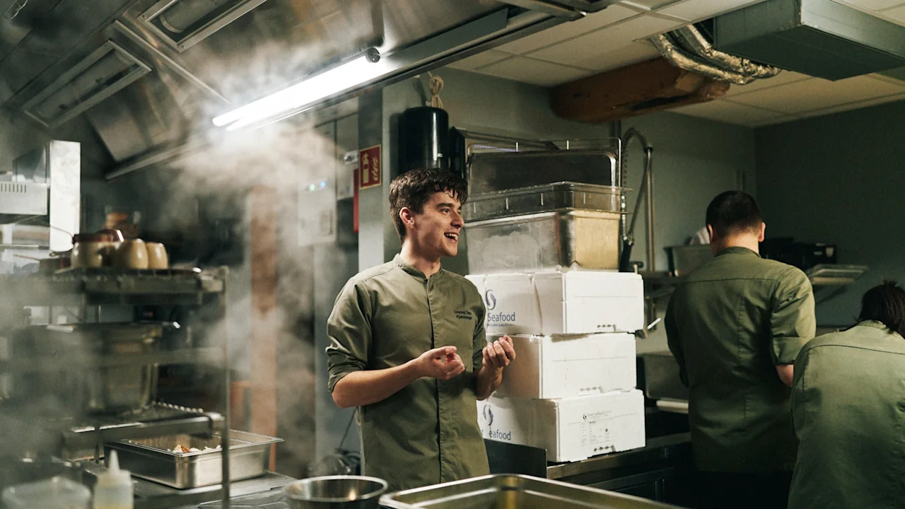 Kokke arbejder i et travlt køkken på Sjøbua, Hotel Brosundet, Ålesund. Damp stiger, mens de tilbereder fiskeretter.