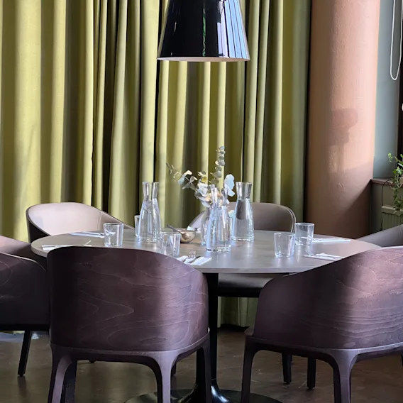 Ett vackert dukat runt matbord med stolar och gröna gardiner, redo för gäster på Quality Hotel Royal Corner.
