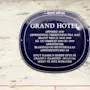 A historical plaque for Home Hotel Grand Bodø, detailing its construction, a fire, renovations, and a famous author's stay.
