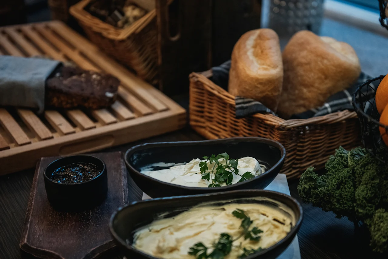 Et indbydende udvalg af friskbagt brød, cremede dips garneret med urter og levende grøntsager, klar til et måltid.