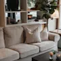 A warm and inviting living space featuring a plush sofa, a coffee table with flowers, and a bookshelf with decor.