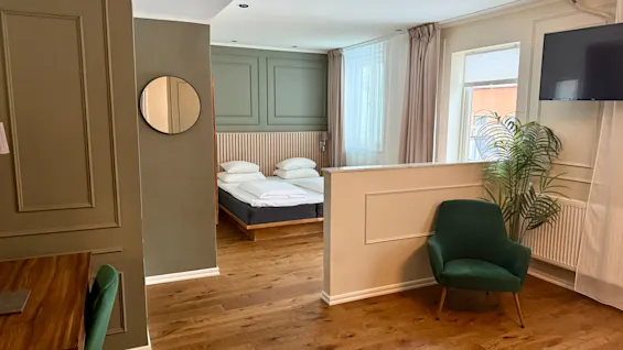 Moderni juniorsviitti, jossa on viihtyisä makuutila ja tyylikäs oleskelutila vihreällä nojatuolilla. Juniorsviitti, Comfort Hotel Linköping City.
