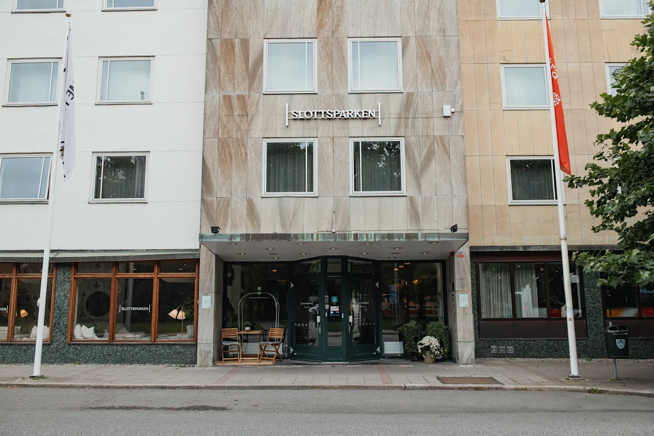 A building facade with a welcoming entrance, outdoor seating, and the sign SLOTTSPARKEN prominently displayed.