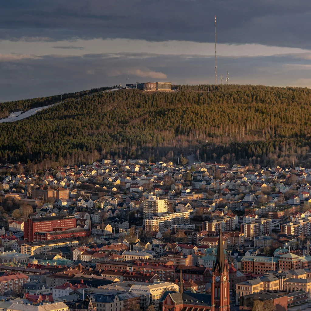 Kultainen tunti valaisee Sundsvallia ja Norr Bergetiä, näyttäen kirkontornin, kaupunkirakennuksia ja metsäisen kukkulan.