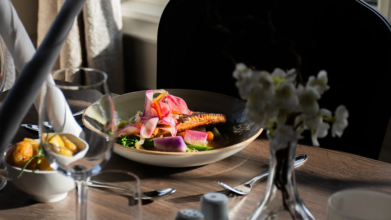 En vackert upplagd måltid med fisk och färgglada grönsaker på ett dukat matbord, redo för en trevlig middagsupplevelse.