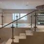 Sisätilojen spa-alue, jossa on poreallas, modernit lasikaiteelliset portaat ja kierreportaat taustalla.