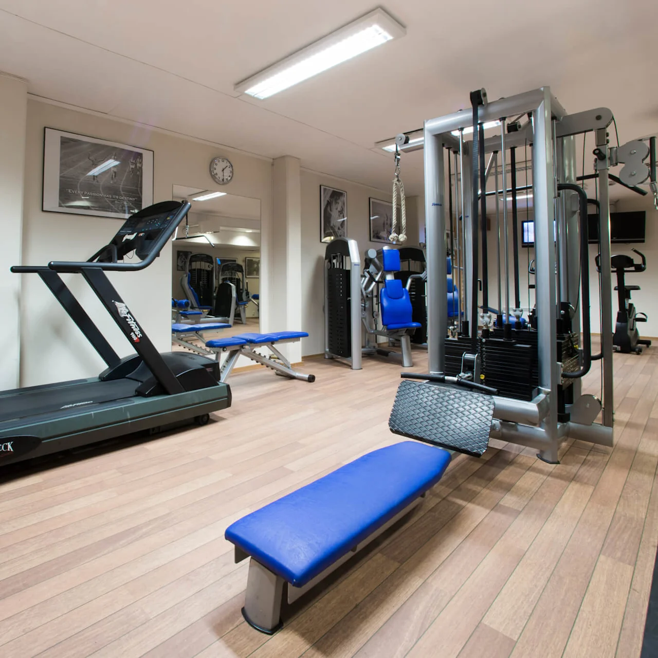 Ett välutrustat, tomt gym med olika träningsmaskiner på ett trägolv.