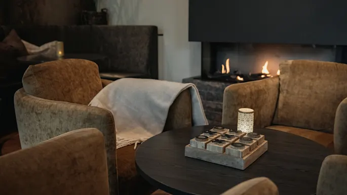 Et koselig salongområde på Home Hotel Norre Park i Halmstad med komfortable lenestoler, et rundt bord og en varm peis.