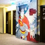 A mural depicts a caped superhero with wings, flanked by flying creatures, next to hotel room doors numbered 501 and 517. Text reads: "Not every flying creature is a superhero. You should have talent."