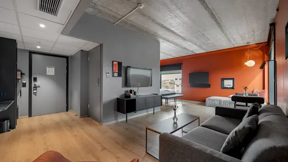 Comfort Hotel Porsgrunn: Et moderne hotellrom med stue, TV og seng. Sikkerhetsskilt synlige.