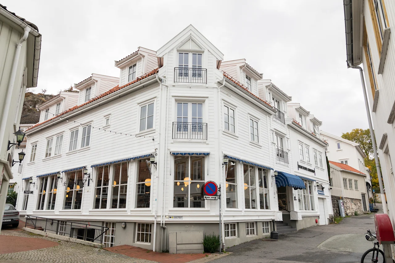 A charming white building with blue awnings on a street corner, housing a restaurant on the ground floor.