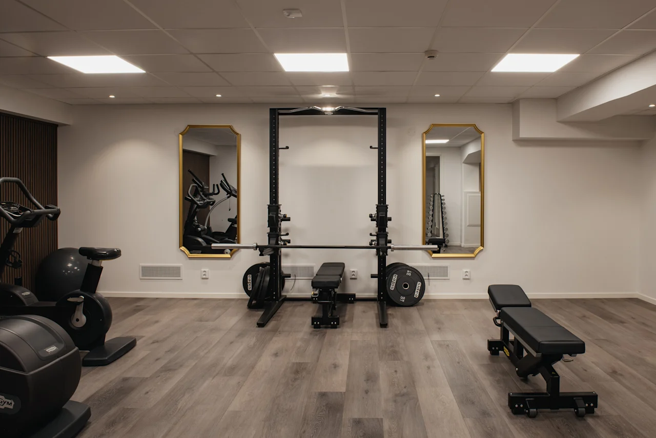 Ett välutrustat gym med konditionsmaskiner, styrketräningsutrustning och speglar, redo för ett träningspass.