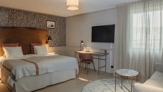 A comfortable hotel room with a large bed, a desk, and a seating area, designed for relaxation and work.