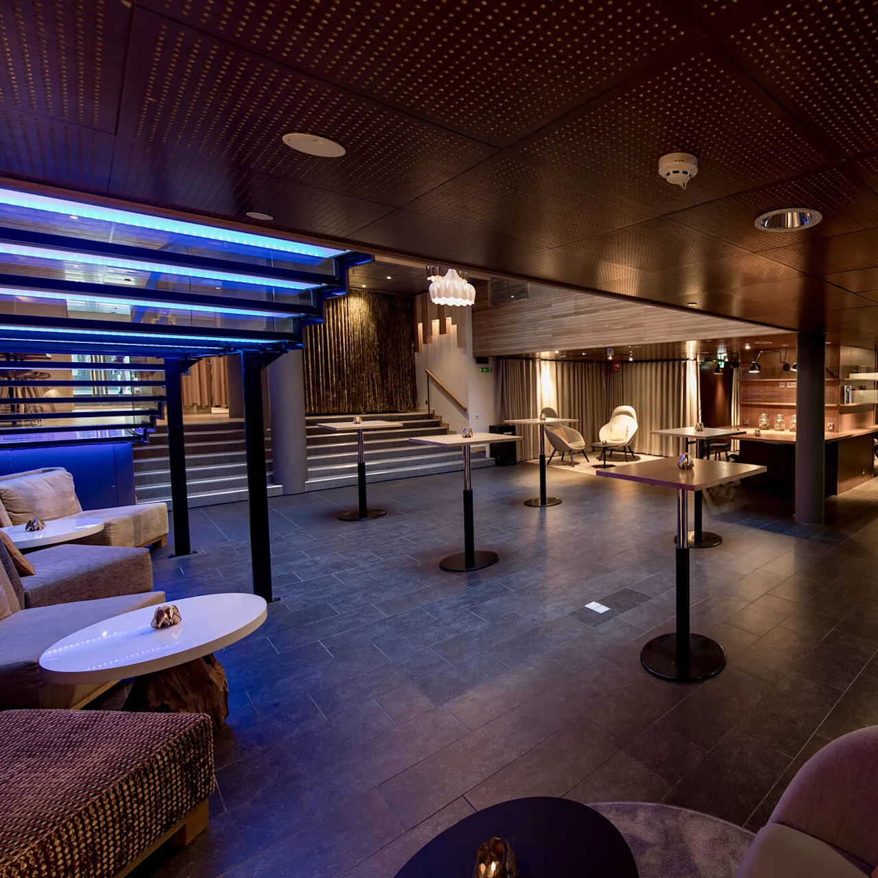 Tilava, moderni lounge, jossa on pehmeitä istuimia ja pöytiä, on himmeästi valaistu, nykyaikaisilla koristeilla ja baaritiski, luoden viihtyisän tunnelman.
