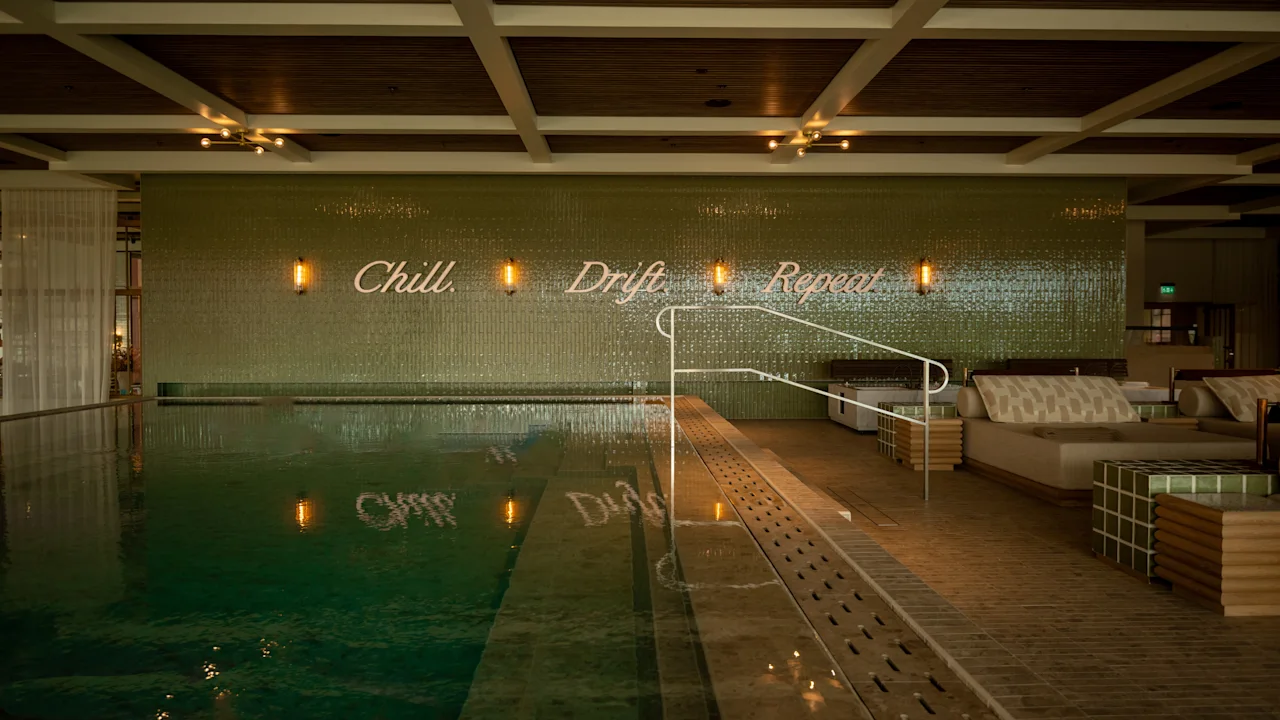 The Dock Spa: Kutsuva sisäuima-allasalue, jossa on oleskelutiloja ja seinäkirjoitus, jossa lukee Chill, Drift, Repeat.