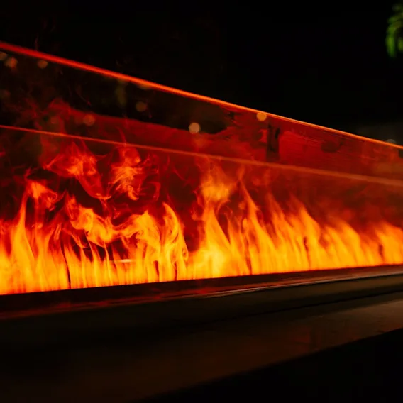 Nærbilde av levende oransje flammer som danser i en moderne glasspeis.