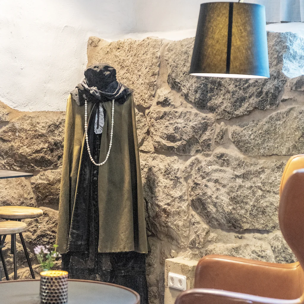 Lobby på Home Hotel Victoria. En mannequin i et historisk-inspireret outfit med perler, en moderne lampe og komfortable siddepladser.