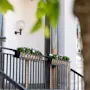 An elegant outdoor stairway with floral decorations and a vintage-style lamp on a white building facade.