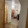 Et flislagt velværeområde med to badekåper hengende, en benk med en pute og en rund matte på gulvet, som inviterer til avslapning.