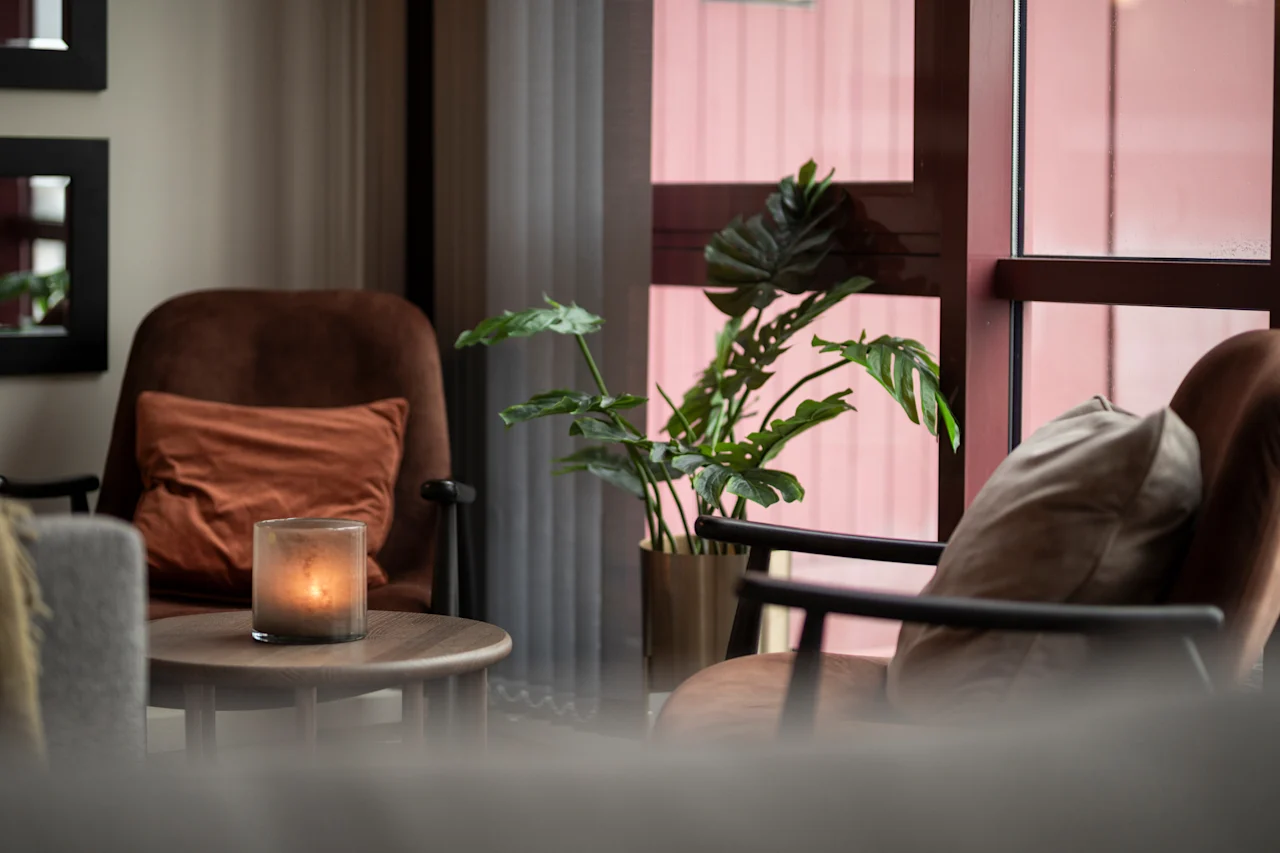 Kutsuva oleskelutila mukavilla istuimilla, lämpimällä kynttilänvalolla ja rehevällä kasvillisuudella ikkunan vieressä.