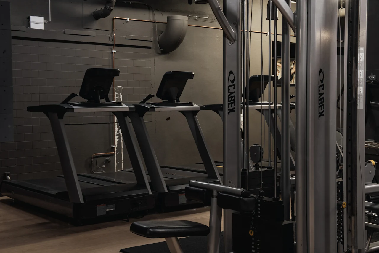 Et moderne fitnesscenter med flere løbebånd og vægtmaskiner, klar til en træning.