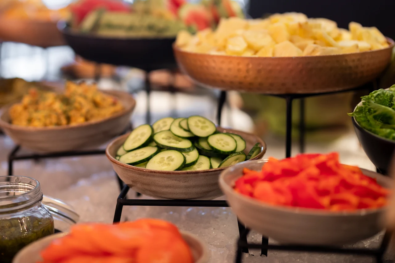 Eloisa noutopöytä, jossa on kulhoja tuoreita, värikkäitä aineksia, kuten viipaloituja kurkkuja ja pilkottuja punaisia paprikoita.