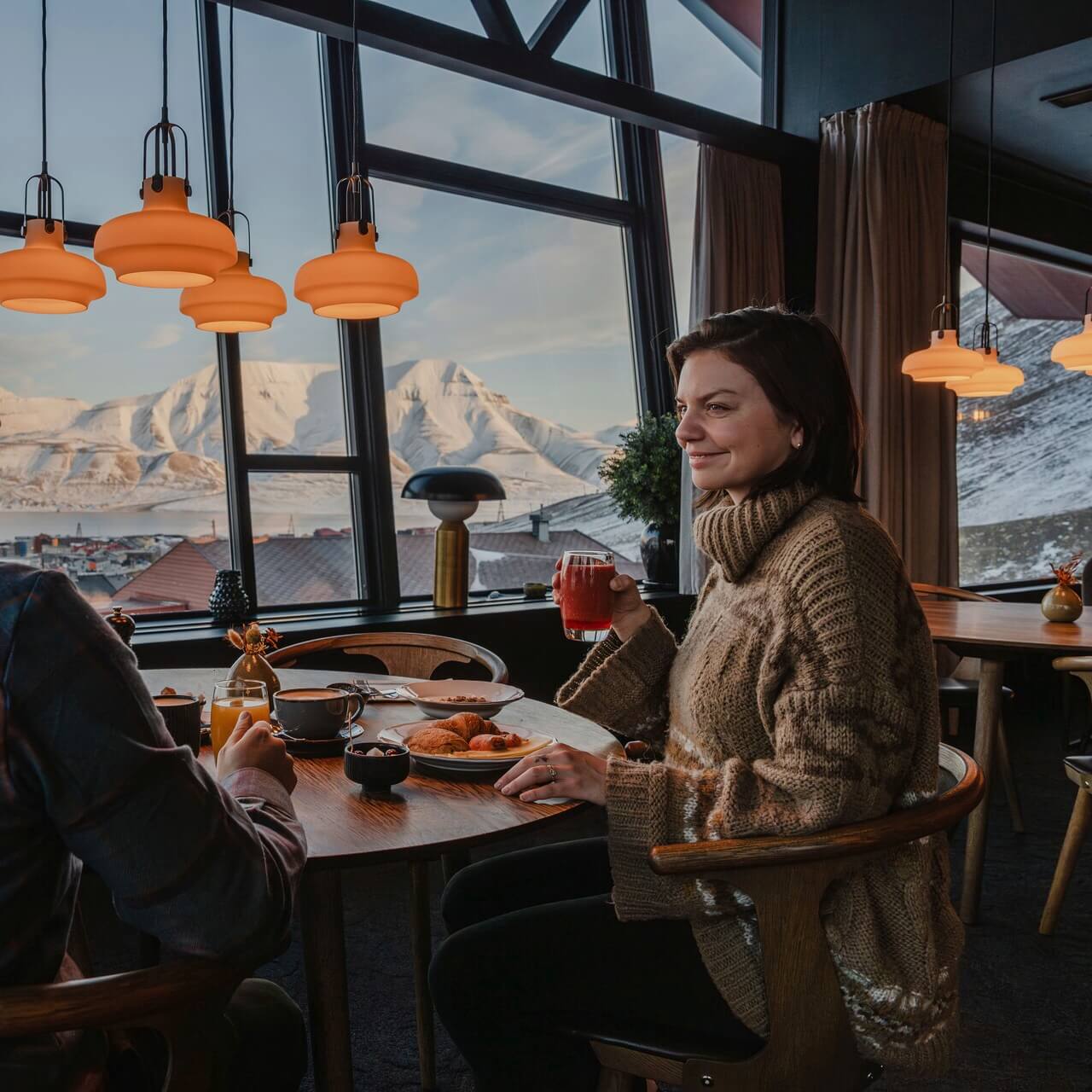 Two people eating breakfast with a magic view at Funken Lodge in Svalbard.