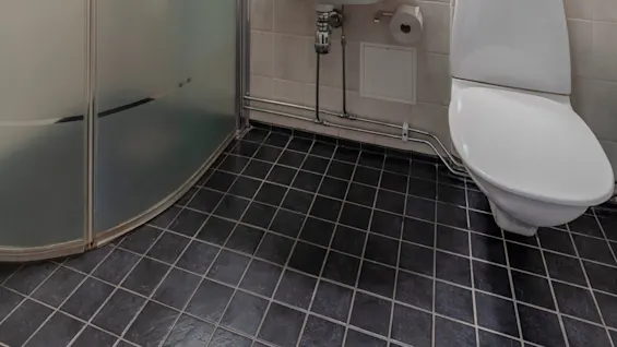 A bathroom with beige walls, a shower cabin, a toilet, and a sink with a mirror above it.
