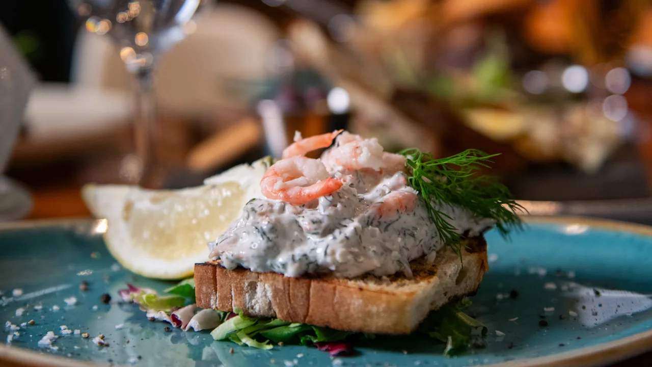 En lækker rejetoast med dild og en citronbåd på en blå tallerken på Clarion Hotel Orebro.