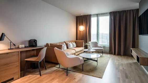 Et romslig og innbydende oppholdsrom med sofa, lenestoler og skrivebord, del av en Juniorsuite på Quality Airport Hotel Værnes.