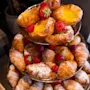 Bakverk på et etasjefat, med croissanter og sitronterter toppet med jordbær og bringebær, dekorativt arrangert på et bord.