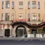Byggnadsfasad visar "HOTEL DROTT" i röd neon, med välvda ingången omgiven av växter. Området inkluderar fönster och skyltar för "DROTT LOUNGE" och "DROTT BAR".