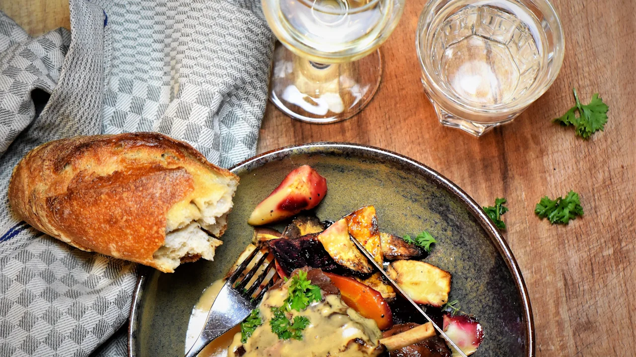 A gourmet meal with a main dish, roasted vegetables, fresh bread, and beverages, ready to be enjoyed at Home Hotel.