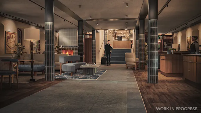 Hotellobby med en gjest som ankommer, en resepsjon og et koselig salongområde med peis. 