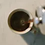 Coffee being poured from a French press into a mug, seen from a top-down view.