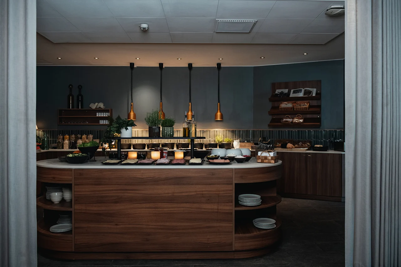 An inviting buffet spread featuring fresh salads, cold cuts, and bread, ready for guests to enjoy in a modern dining area.